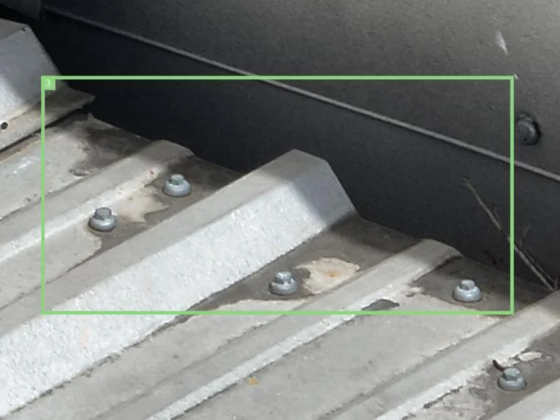 Close-up aerial photo of the CrossFit eXalted roof surface showing a section marked for repair inspection