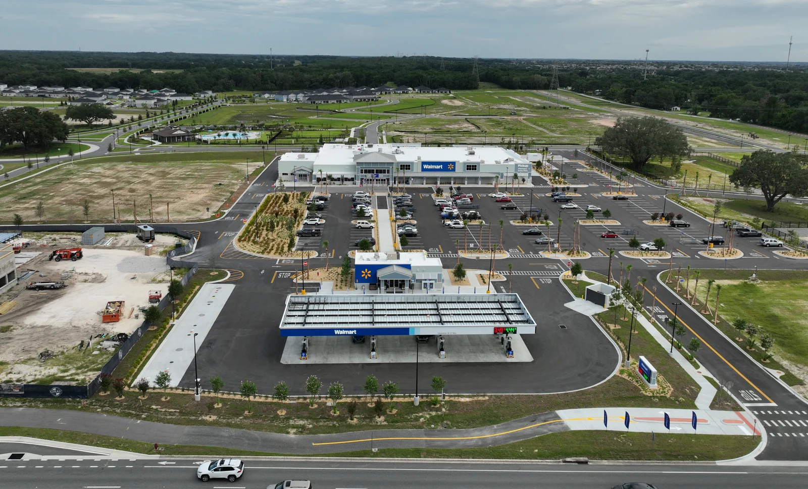 Front-elevation drone view of the completed Walmart Supercenter with gas station in Lady Lake, Florida at the end of the 11-month weekly aerial documentation engagement, showing the Walmart storefront, the fueling canopy, the parking lot, and the site landscaping in their final configuration, captured June 25, 2026.